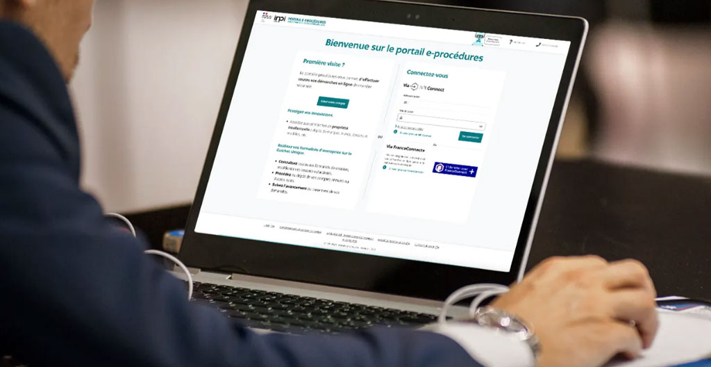 Écran d'ordinateur affichant l'interface du guichet unique INPI avec documents administratifs de création SCI disposés sur le bureau